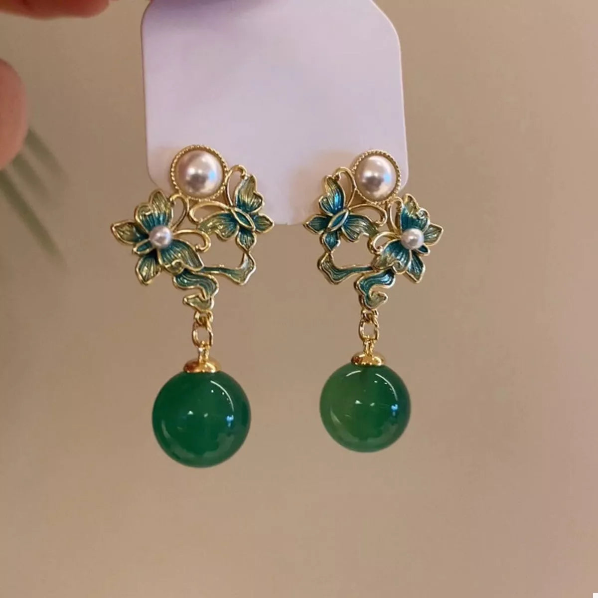 Dark green butterfly pearl drop earrings with floral accents.