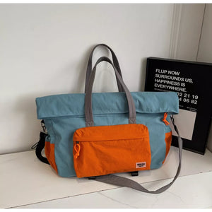 Duffel bag in blue with orange front pocket and grey straps.