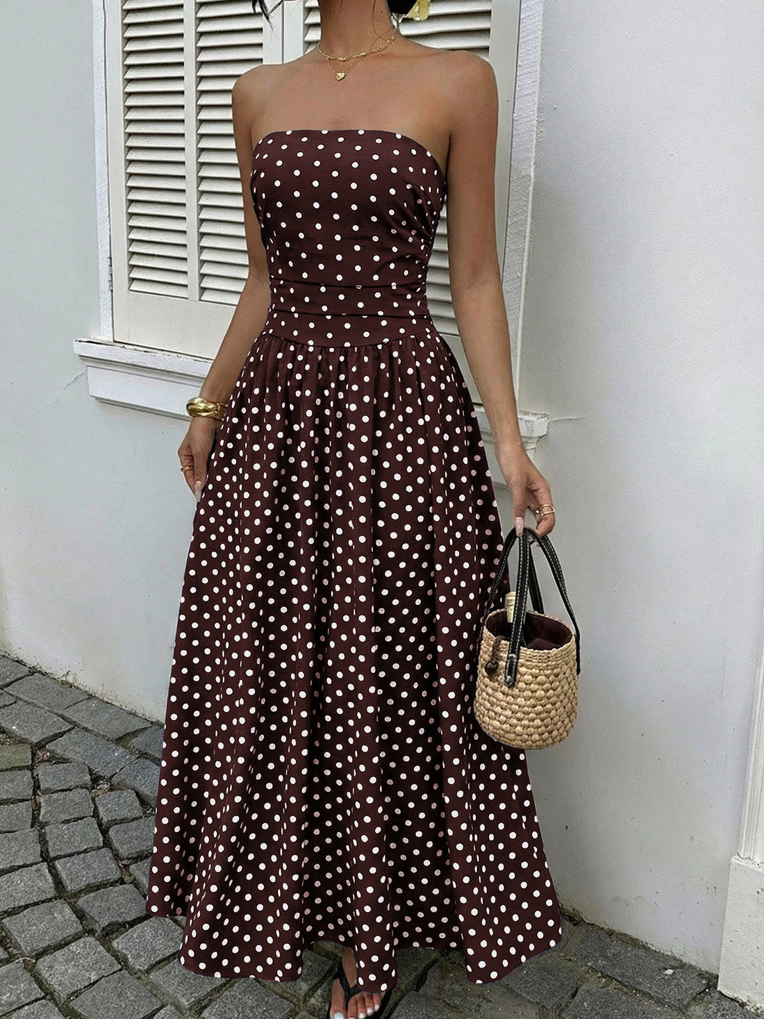 Brown polka dot A-line maxi dress with strapless neckline and cinched waist.