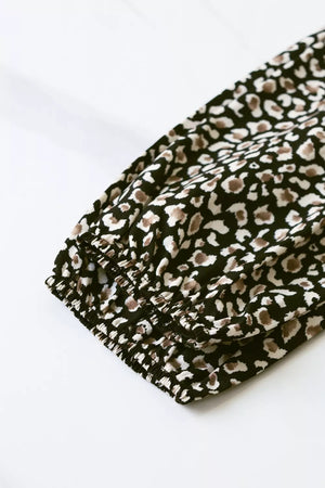 Chic midi dress with balloon sleeves in black animal print, featuring elasticated cuffs.