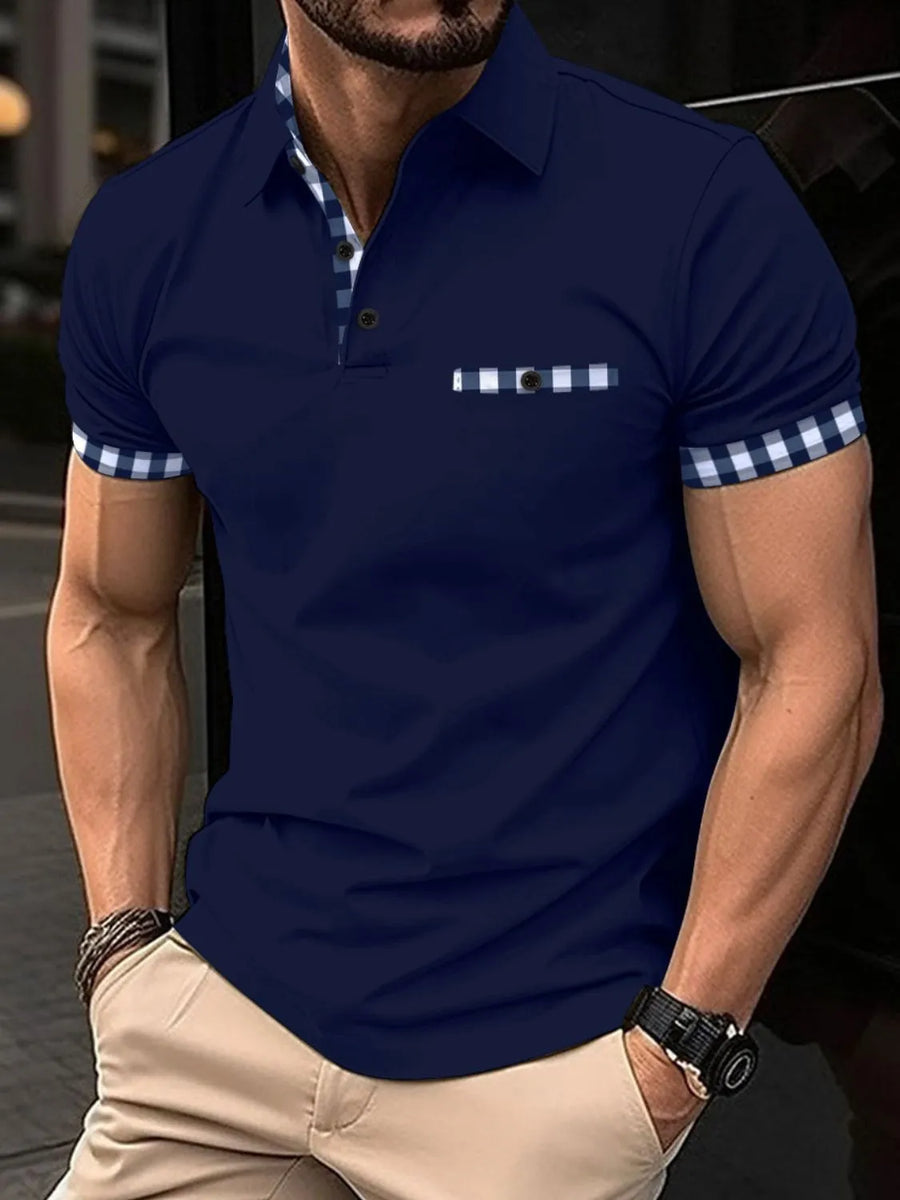 Navy polo shirt with checkered trim on collar, pocket, and sleeves.
