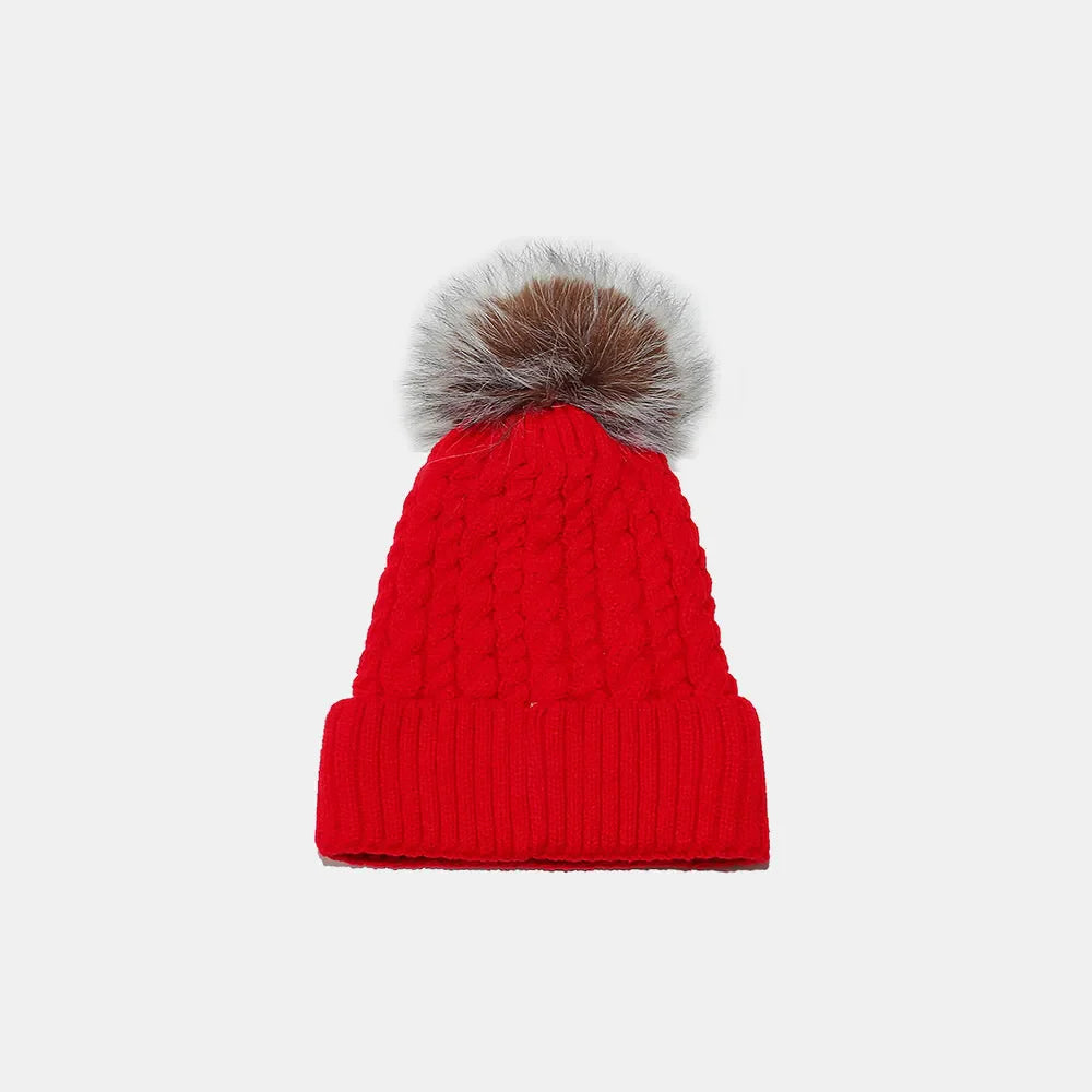 Red cable knit beanie with a fluffy pompom and ribbed cuff.