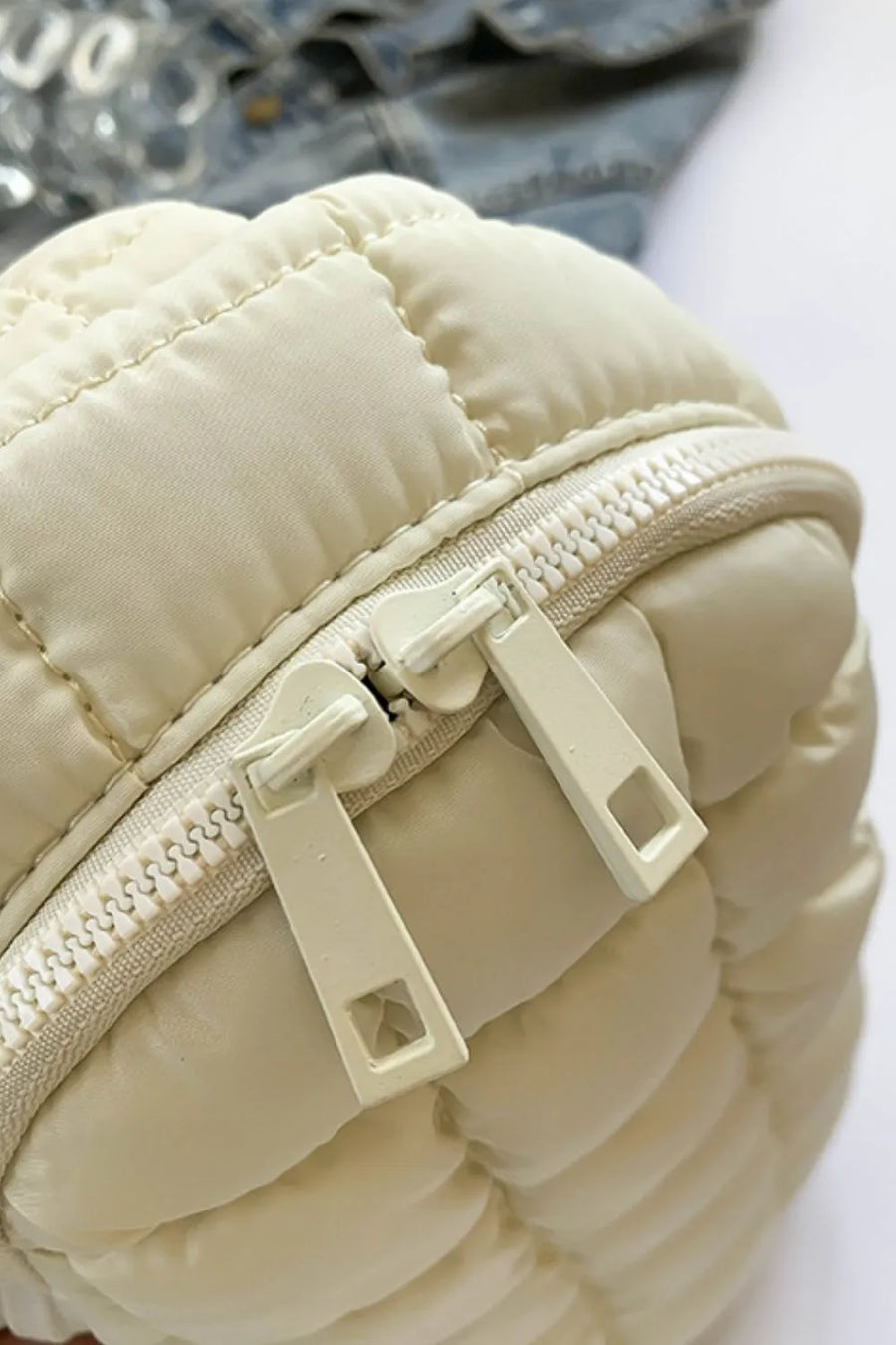 Padded sling bag in Ivory with quilted detail and double zippers.