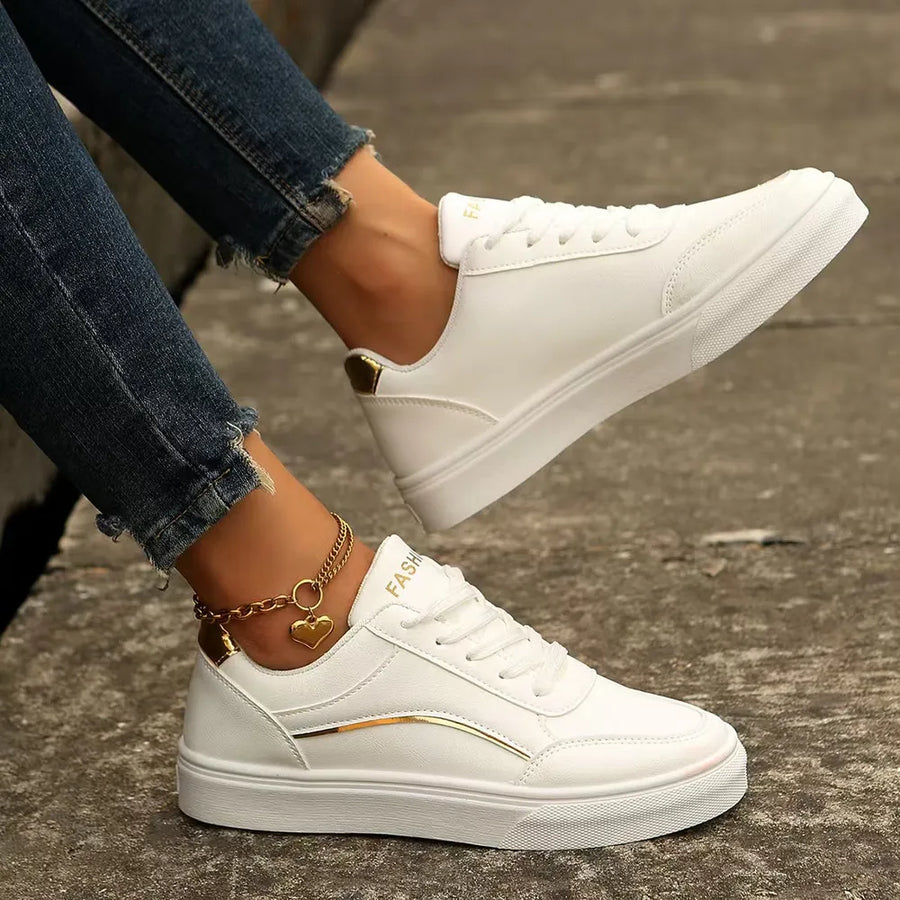 White sneakers with gold metallic trim and heel detail, lace-up closure.