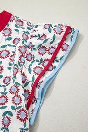 Vibrant floral midi dress in cotton with red, blue, and green flowers, red neckline trim, and light blue hem trim.