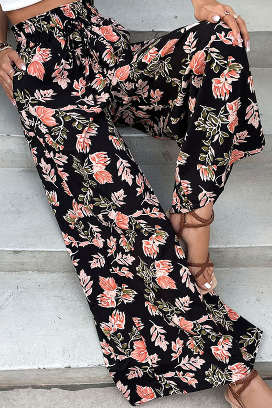Black palazzo trousers with a floral print and drawstring waist.