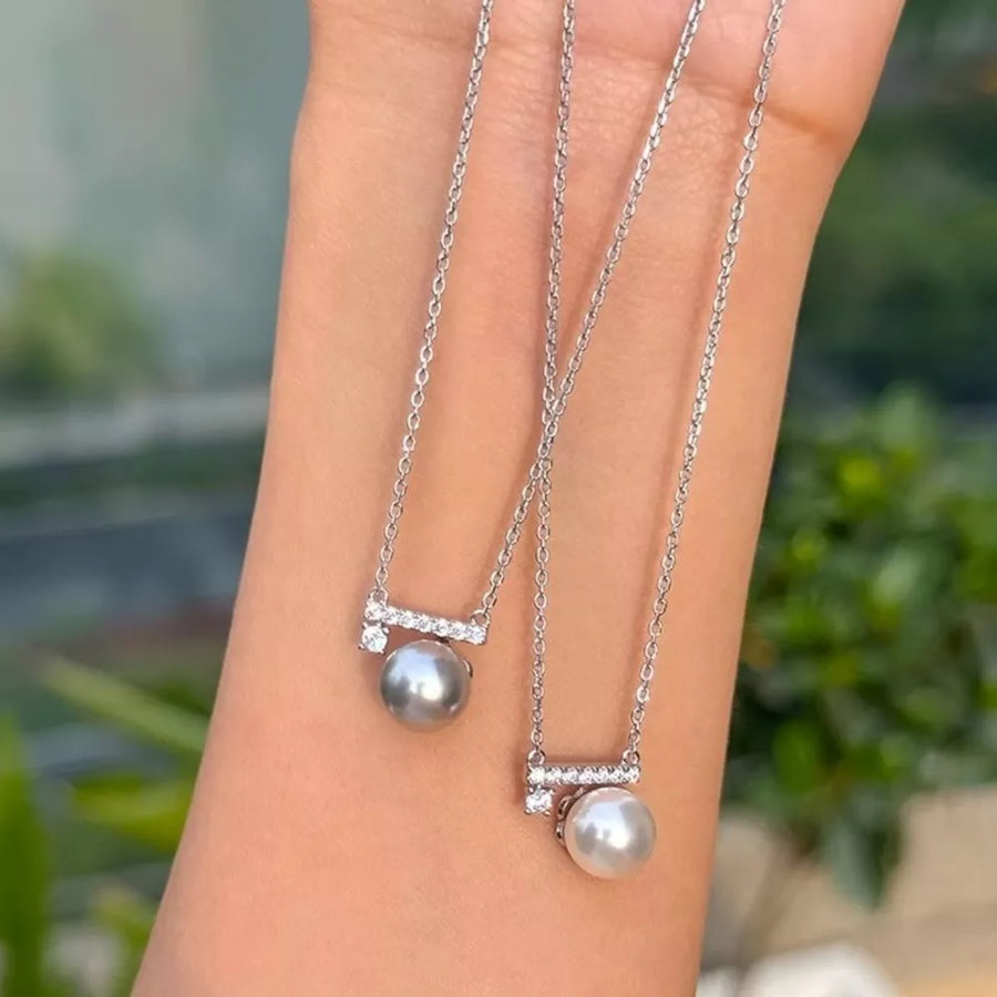 Lustrous pearl pendant necklace with zircon accents on a silver chain, shown in light gray and cream.