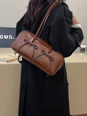Brown patent leather shoulder bag with bow details and a top handle.