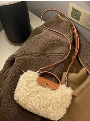 Textured mini crossbody bag in cream fuzzy material with brown leather trim and strap.
