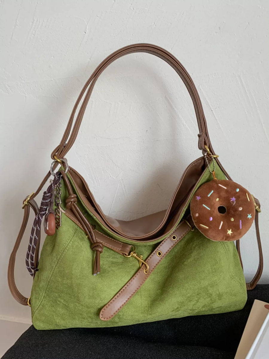 Sage green hobo bag with brown trim, adjustable strap, and donut charm accessory.