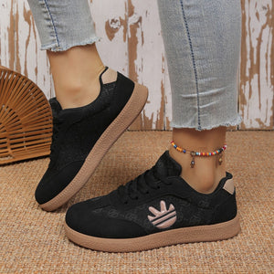 Black lace up sneakers with all over pattern and tan sole.