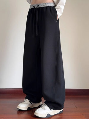 Men's black drawstring wide-leg sweatpants with a gray waistband.