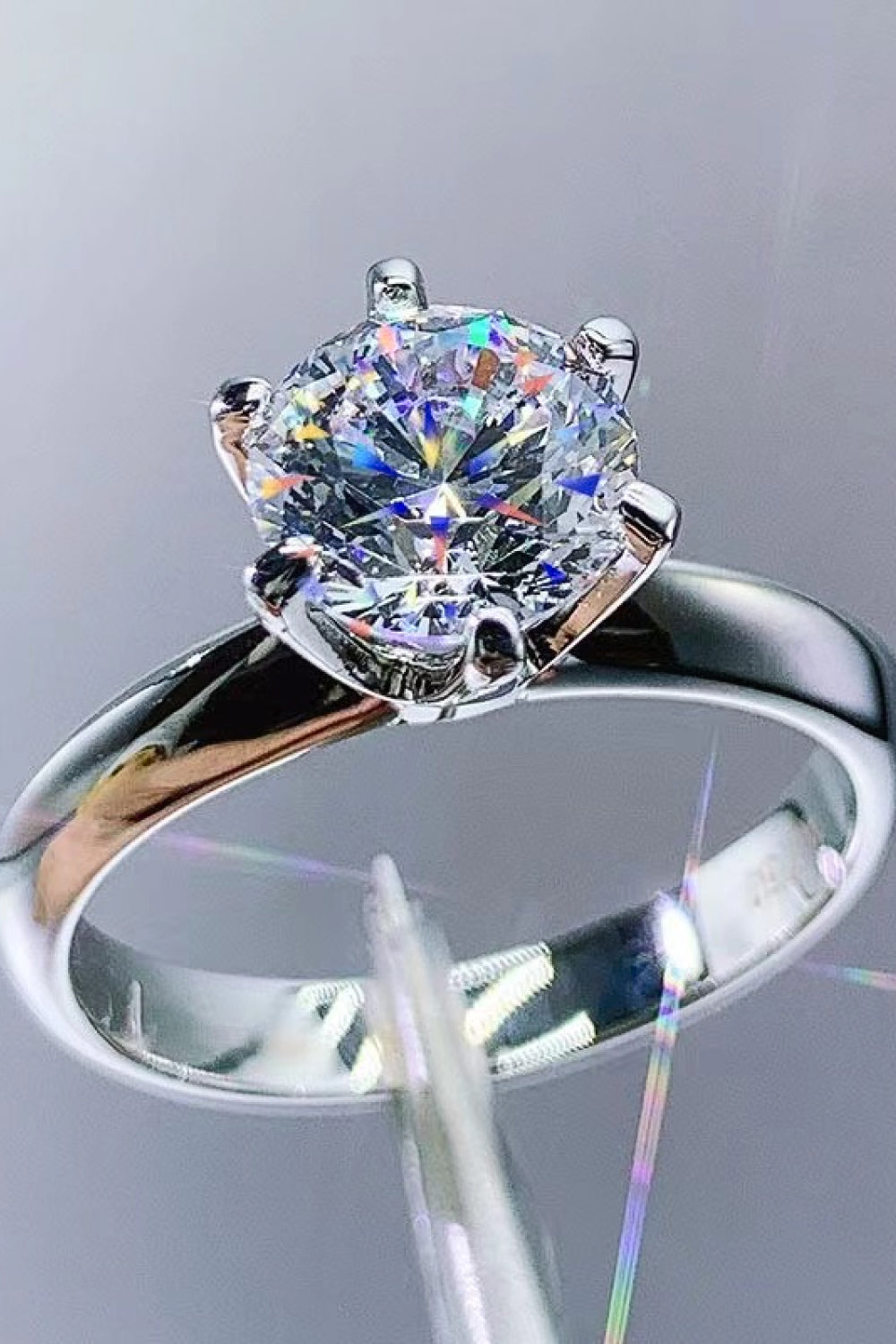 Silver engagement ring with a brilliant cut moissanite stone in a six-prong setting.