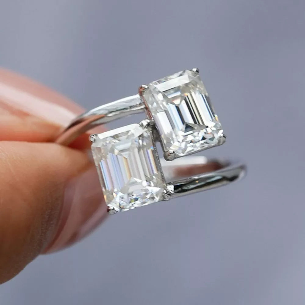 Emerald-cut moissanite bypass ring in silver with two large stones.