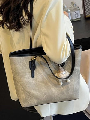 Distressed pu leather tote bag in dark gray with buckle accents and a fuzzy charm.