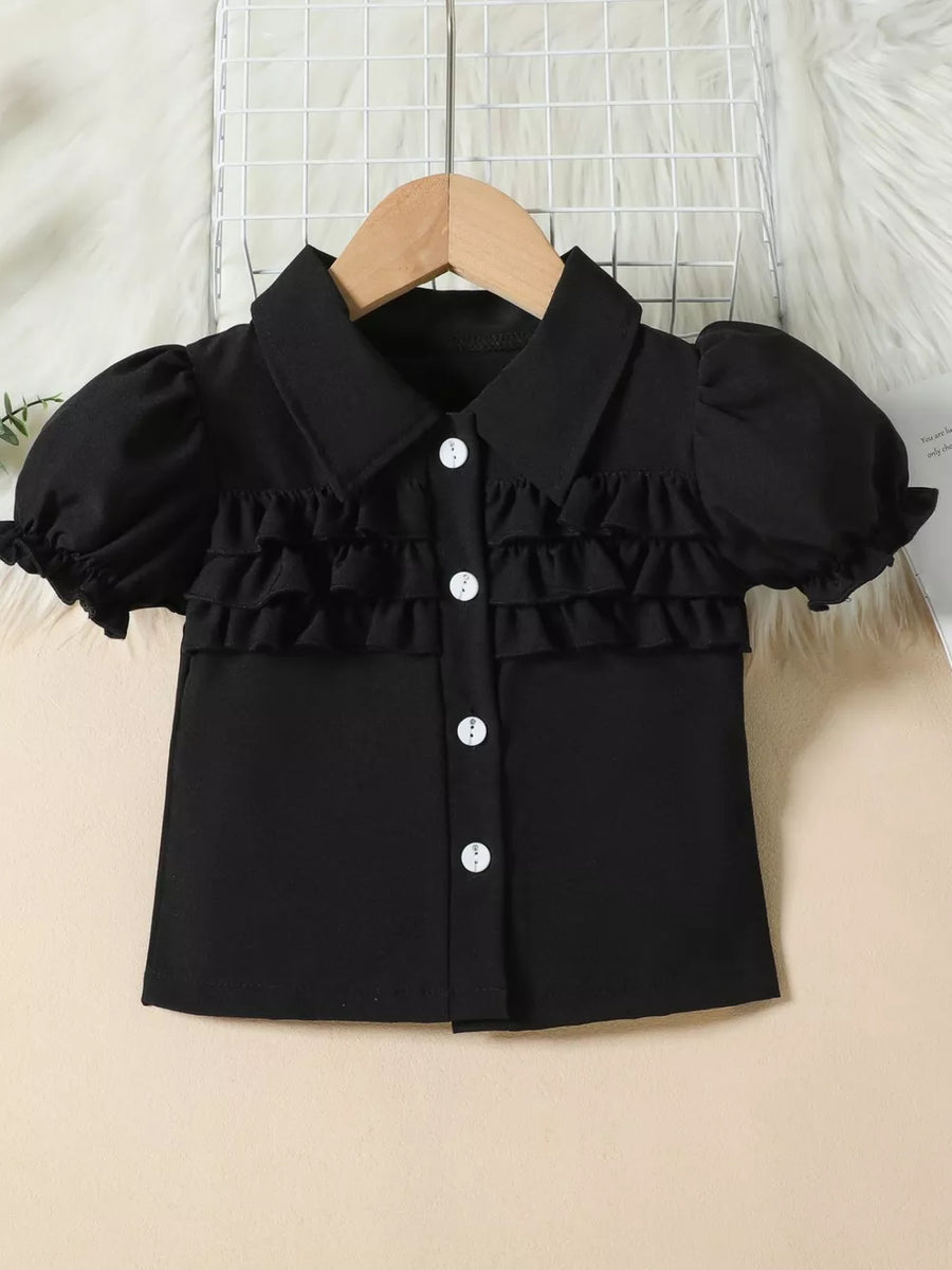Black baby top with puff sleeves, ruffles, and white buttons.