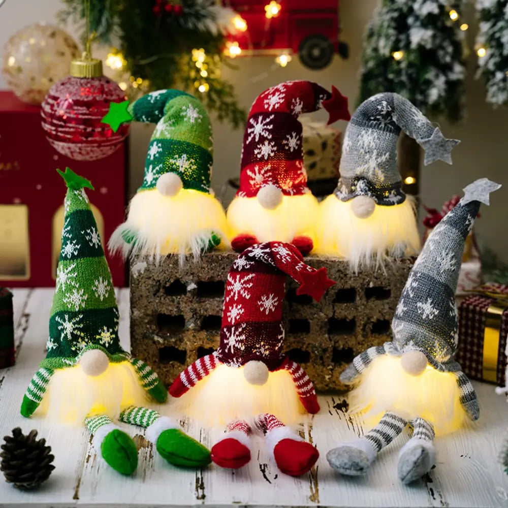 Illuminated knit gnomes in red, dark gray, and dark green with snowflake patterns and glowing bases.