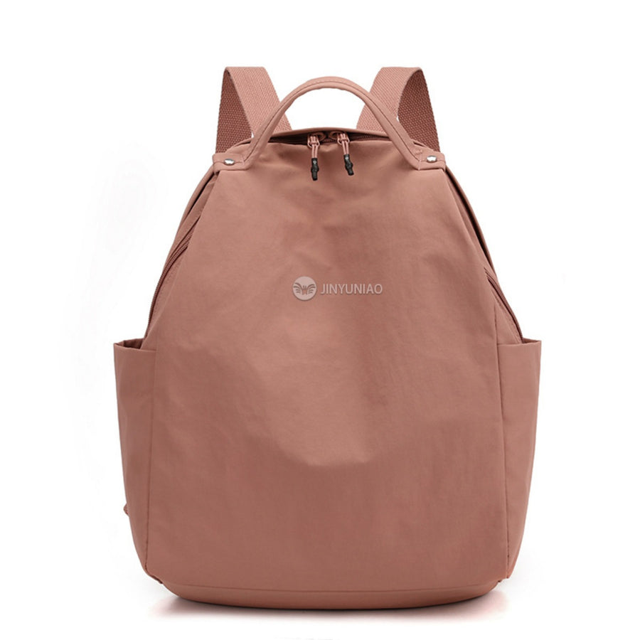 Blush pink nylon lightweight backpack with dual zippers and side pockets.