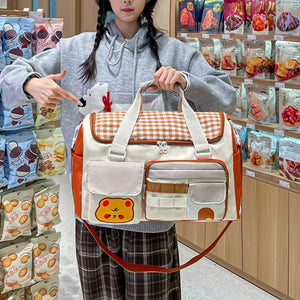 Charming cream travel bag with orange trim, gingham pattern, and cute bear applique.