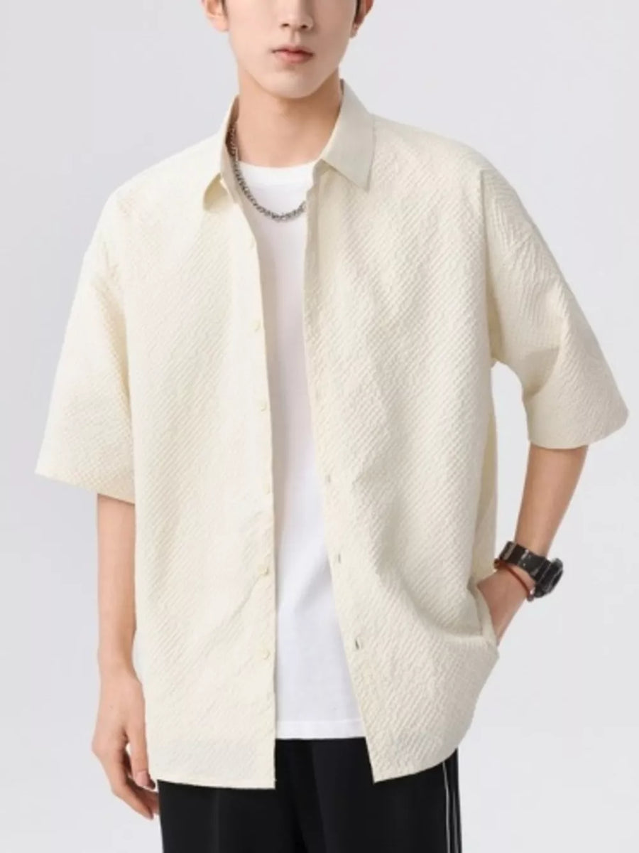 Men's beige textured short-sleeve button-up shirt with a white t-shirt underneath.