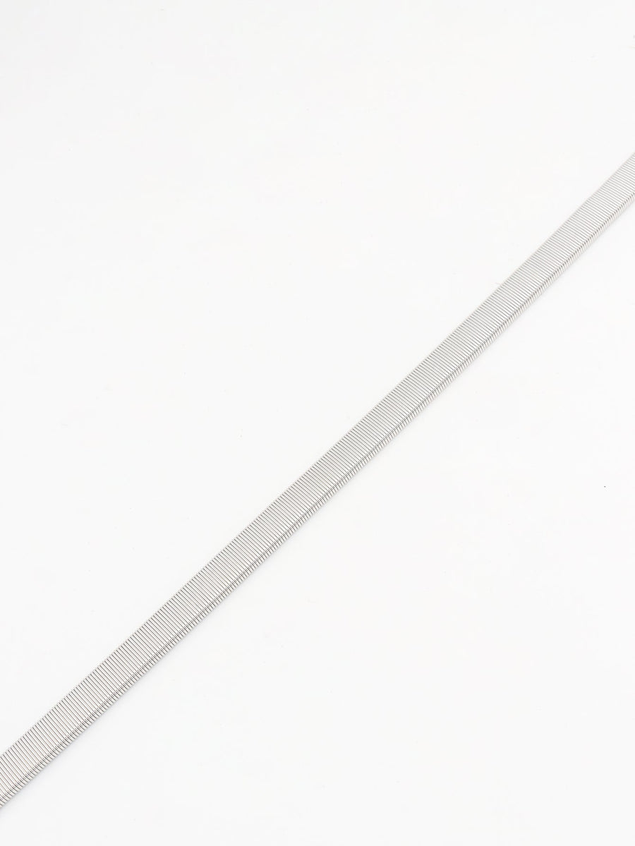 Silver metal mesh belt with a ribbed texture, styled as a waist accessory.