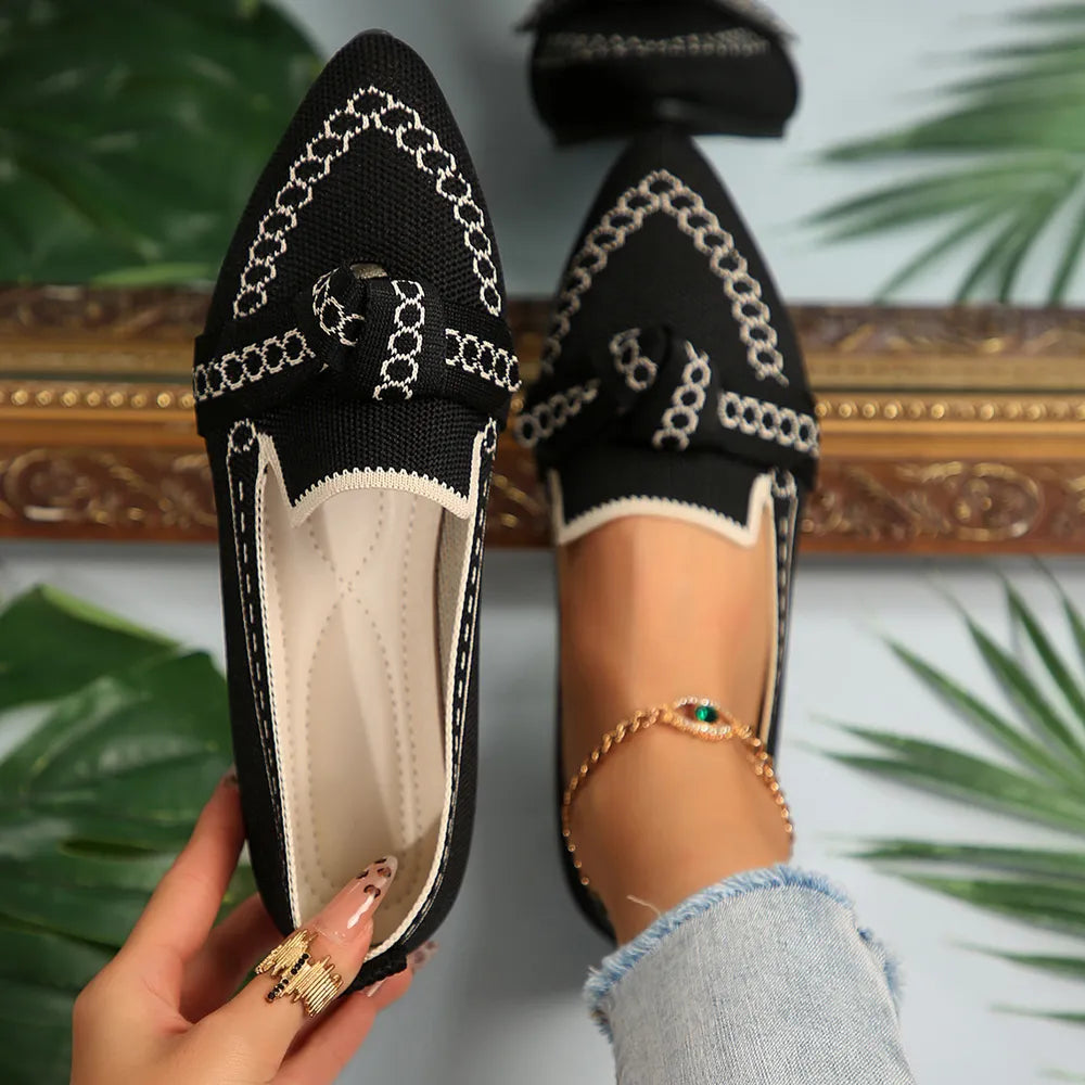 Black chain-stitched knit bow pointed flats with white trim and a bow detail.
