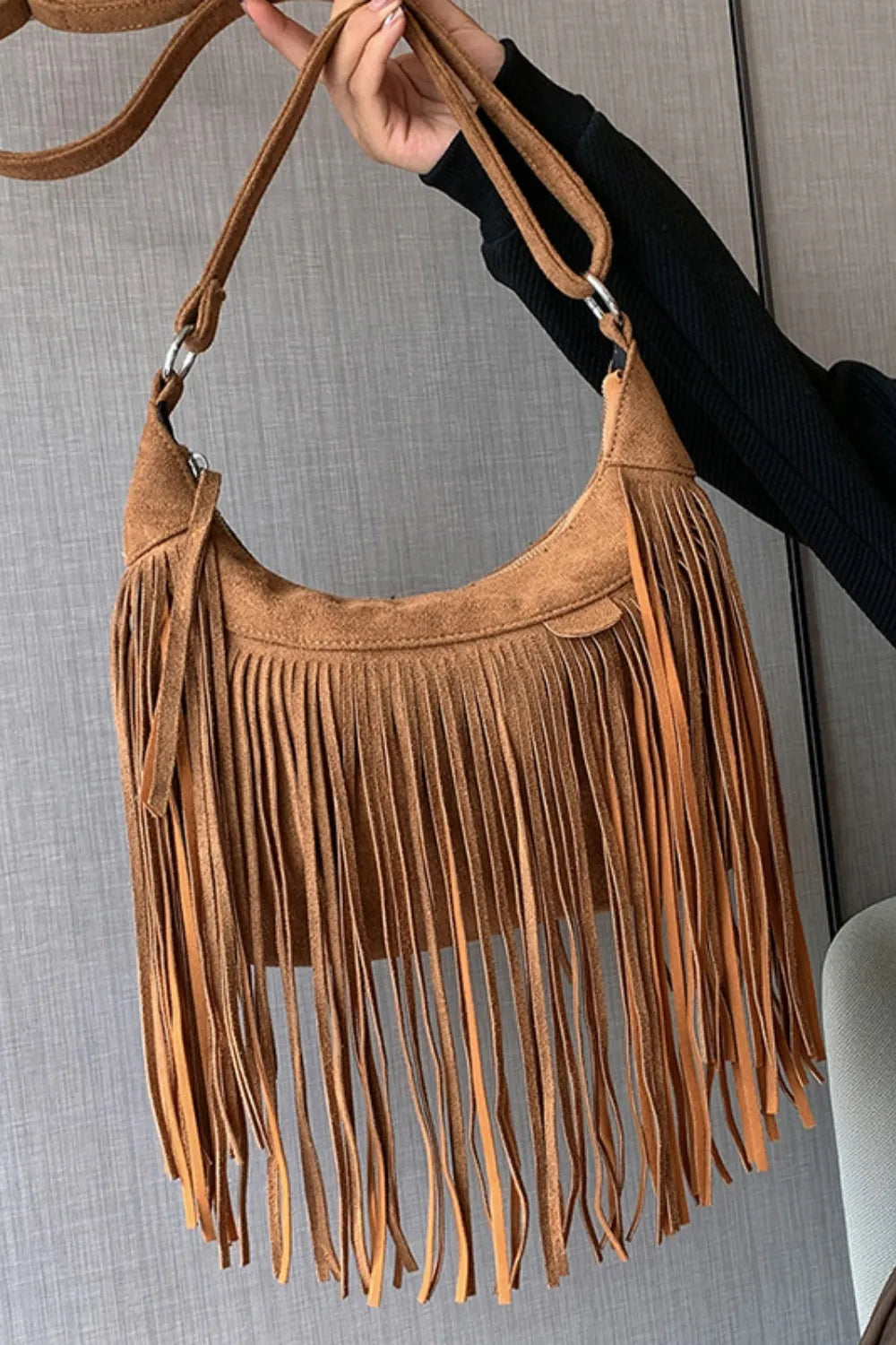 Bohemian suede crescent crossbody bag in caramel with long fringe detail.