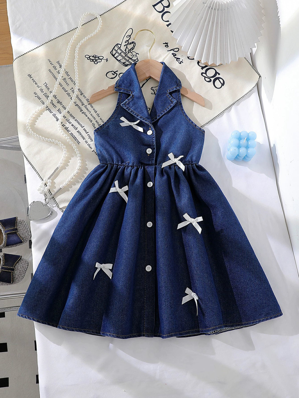 Dark blue denim baby dress with white bowknot details and button-down front.