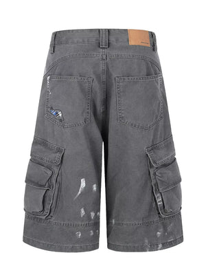 Gray cargo capris with distressed detailing and paint splatters.