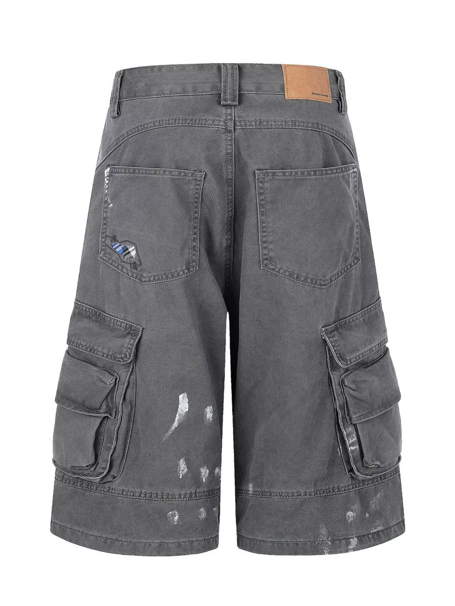 Gray cargo capris with distressed detailing and paint splatters.