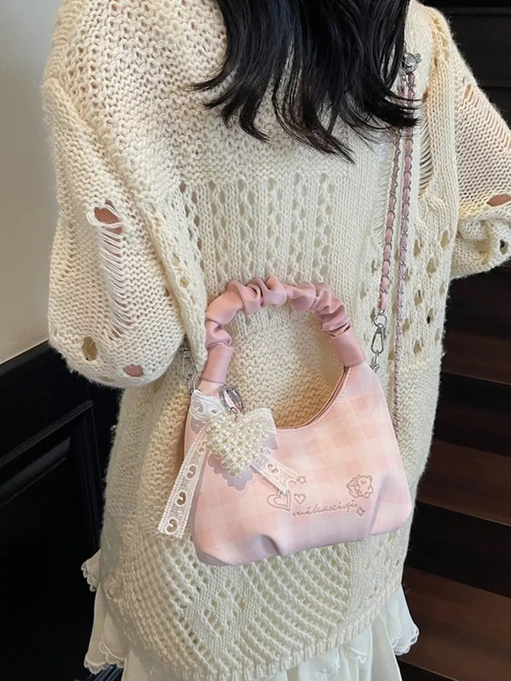 Charming mini crossbody bag in blush pink with ruched handle and pearl bow charm.