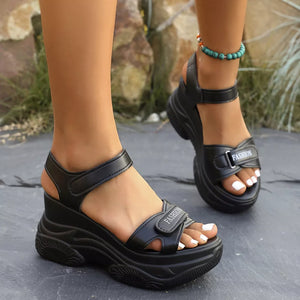 Black open-toe wedge sandals with ankle straps and adjustable closure.