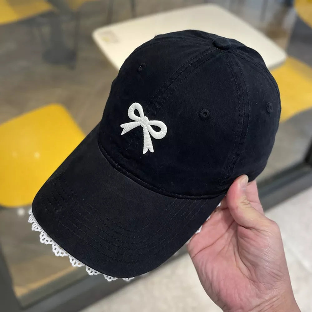 Black baseball cap with embroidered white bow and lace trim