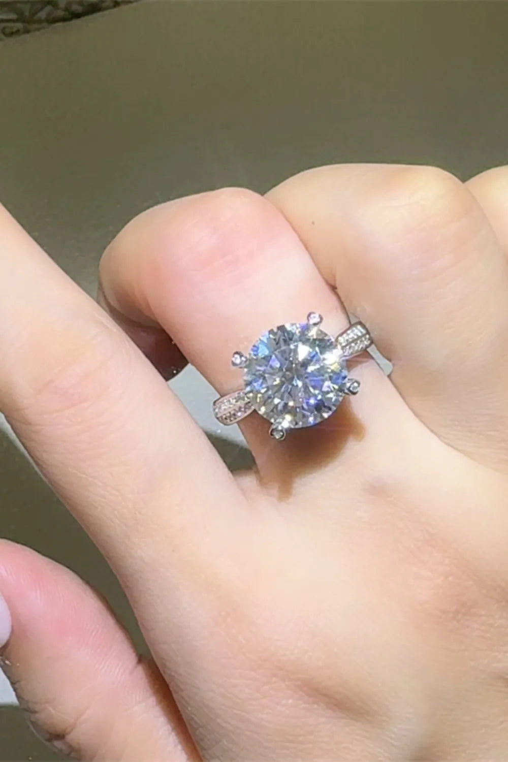 Silver pavé band moissanite engagement ring with a large round center stone.