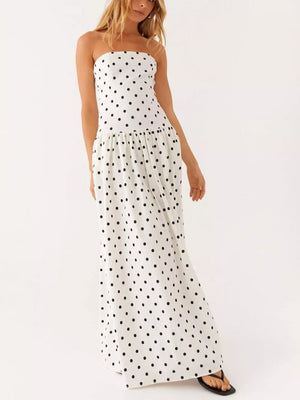 White polka dot strapless maxi dress with tiered skirt and black flip-flops.
