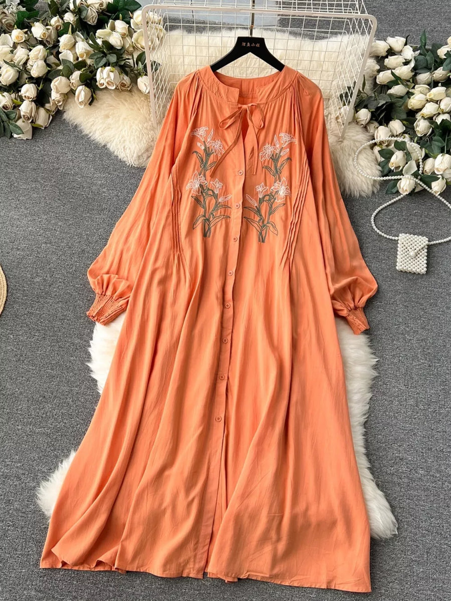 Orange cotton maxi dress with embroidered floral detail and tie neck.