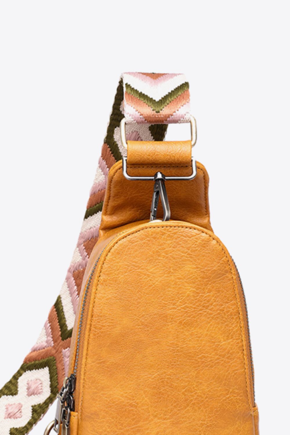 Textured mustard sling bag with a woven chevron strap and silver hardware.