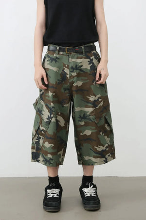Wide-leg camo cargo Bermuda shorts with multiple pockets in green camouflage pattern.