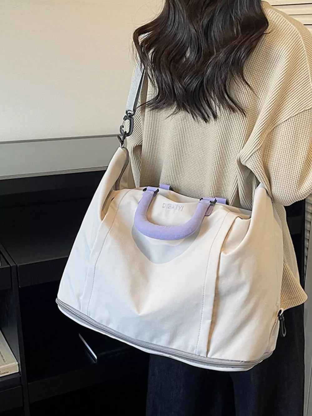 Sleek nylon travel bag in off-white with purple handles and adjustable strap.