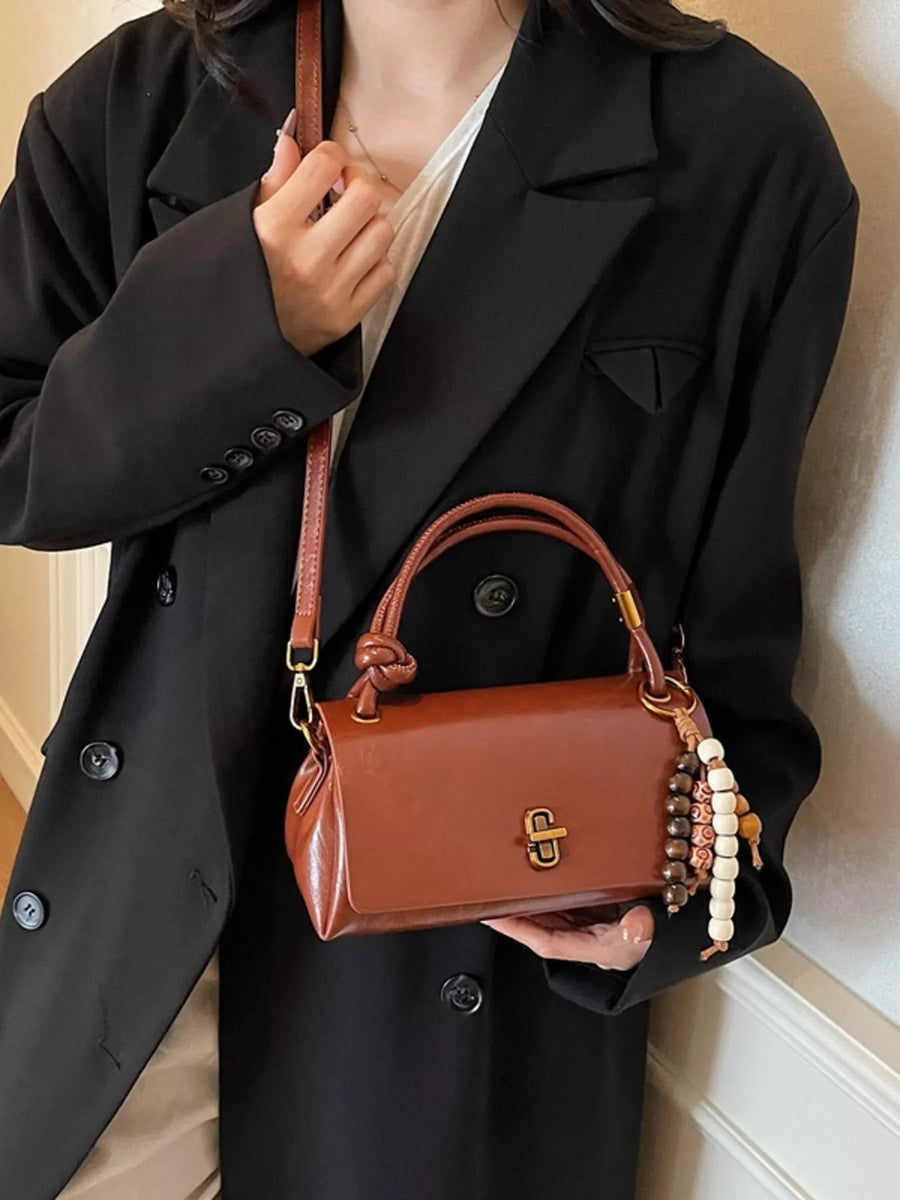 Brown leather crossbody bag with beaded charm and gold clasp detail