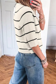 Cream ribbed knit top with black stripes and short sleeves, styled with jeans.