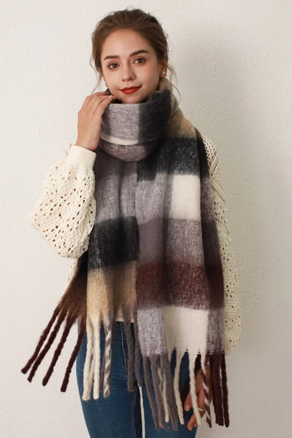 Checked plaid fringed winter wrap scarf in gray/brown grid with fringe detail.