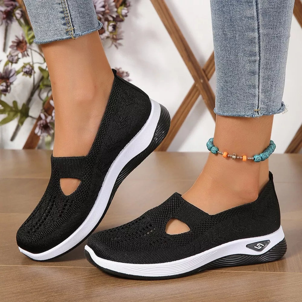 Black breathable mesh slip-on shoes with white soles and a cutout detail.