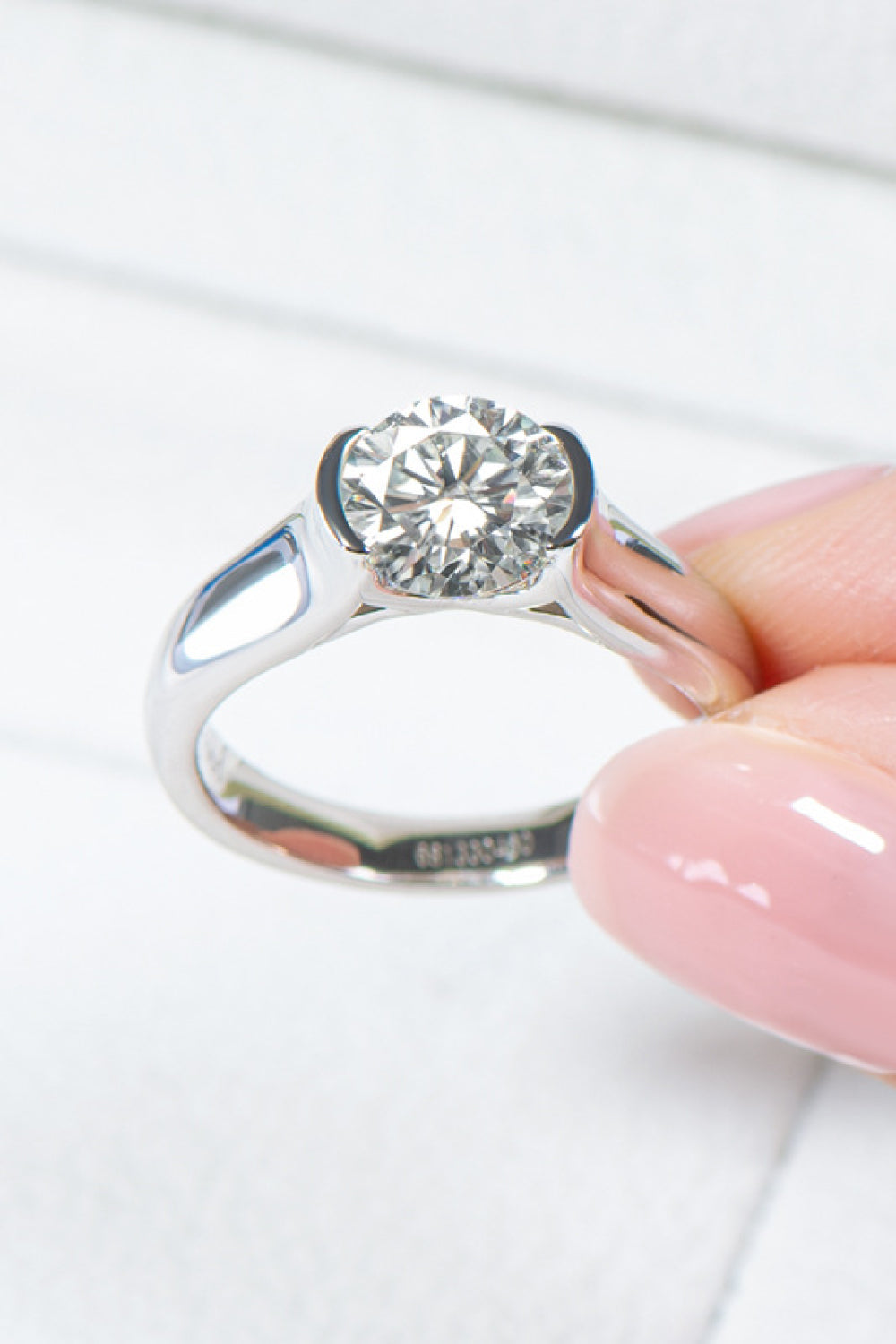 Platinum ring with a round moissanite solitaire stone in a bezel setting.