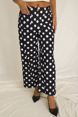 Black polka dot mid-rise trousers with pockets and a button closure.