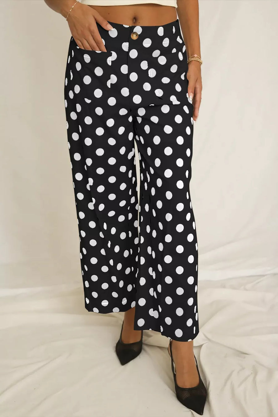 Black polka dot mid-rise trousers with pockets and a button closure.