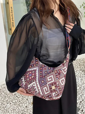 Embroidered geometric hobo bag in burgundy with colorful woven strap.