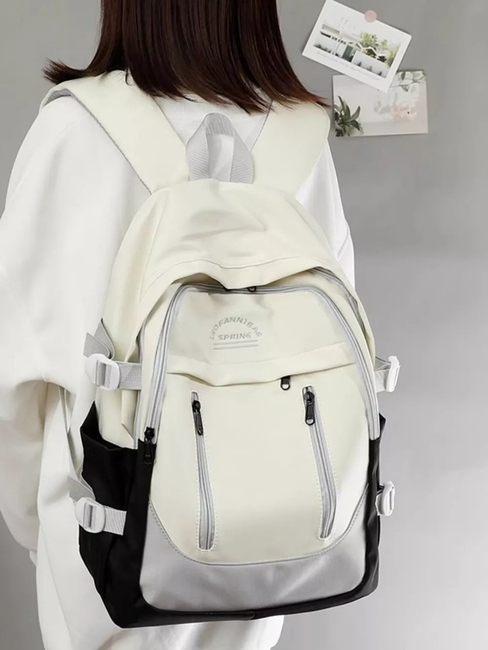 Chic color block nylon backpack in cream, gray, and black with adjustable straps and multiple zippered pockets.