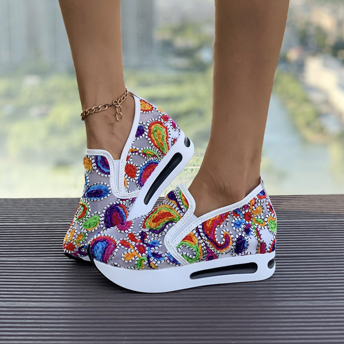 Vibrant slip-on platform sneakers with colorful paisley embroidery and white soles.