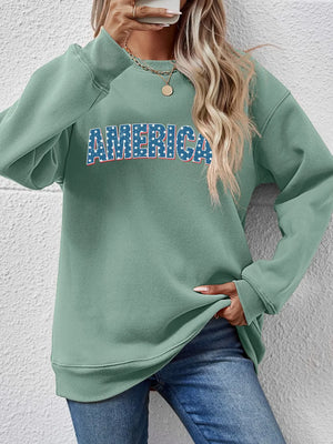 Sage green crewneck sweatshirt with America graphic in red, white, and blue stars and stripes.